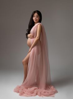 a pregnant woman in a pink gown poses for a photo with her legs spread out