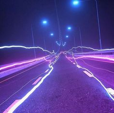 long exposure photograph of street lights in the night time with purple and blue streaks on the road