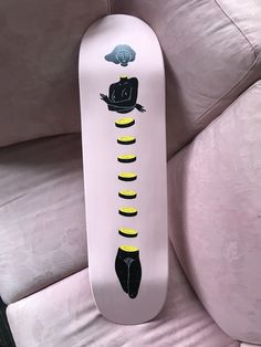 a white skateboard with black and yellow designs on it's bottom part sitting on a couch