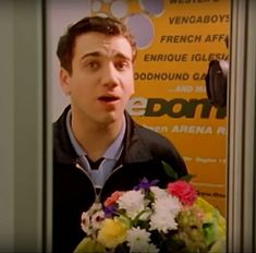 a man holding a bouquet of flowers in front of a sign that says do not enter