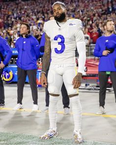 a football player standing on the sidelines in front of an audience with other players behind him