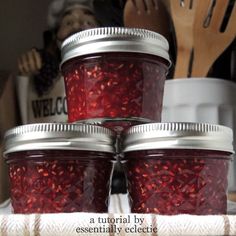 four jars filled with red liquid sitting on top of a table next to utensils