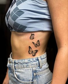 a woman's stomach with three butterflies on her left side, and the lower part of