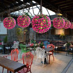 tables and chairs with flowers hanging from the ceiling