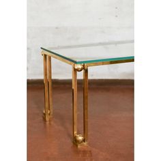 a glass and brass coffee table on a brown floor