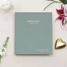 the official wedding album is surrounded by flowers and heart shaped gold hearts on a white surface