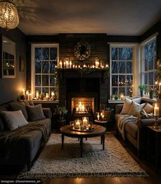 a living room filled with furniture and lit candles on the fireplace mantel in front of a window