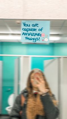 a woman is taking a selfie in front of a sign that says you are capable of amazing things