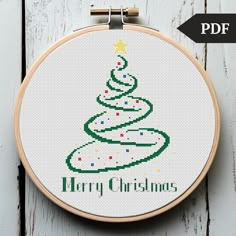 a cross stitch christmas tree on a white wooden background