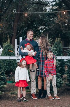 a family standing in front of christmas trees