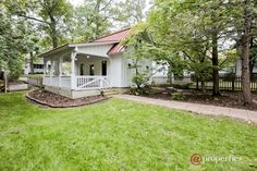 a small white house sitting in the middle of a lush green yard with lots of trees