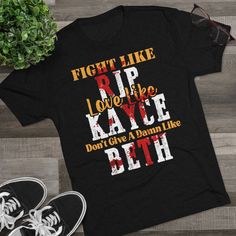 "✦Product Name: Fight Like Rip Love Like Kayce Don't Dive A Damn Like Beth ✦Materials: 50% polyester, 25% combed ring-spun cotton, 25% rayon   ✦Color: 6 Colors Available  ✦Size: S, M, L, XL, 2XL ✦Pre-Shrunk: Yes ✦Singles: 32 ✦Tear Away Label: Yes  ✦Weight: 4.3 Oz/y2 (146 g/m2) ✦True to Size: Yes  ✦Shoulder Taping: Yes ✦Machine Washable: Yes ✦Package: 1x Unisex Shirt Attention Yellowstone fans of the world, if you are looking for the perfect graphic tee, then you came to the right place. \"Fight Like Rip Love Like Kayce Don't Dive A Damn Like Beth\" graphic tee is a guaranteed show stopper. You will be the envy of all the Yellowstone fans around town. This fitted t-shirt is a staple in many women's wardrobe collections. It's soft, form-fitting, and pre-shrunk, so it will maintain its shape Yellowstone Tv Show, Rip Love, Yellowstone T Shirts, Dutton Ranch, Beth Dutton, Rose Shirts, Chic Shirts, The Chic, Unisex Shirt