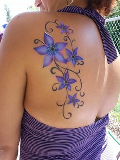 a woman with purple flowers painted on her back shoulder and chest, wearing a purple dress