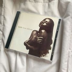 a cd case sitting on top of a bed covered in white sheets and blankets, with the cover pulled back