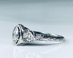 an antique style diamond ring with filigrees on the band and center stone