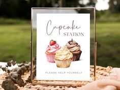 a cupcake station sign sitting on top of a table next to an open book