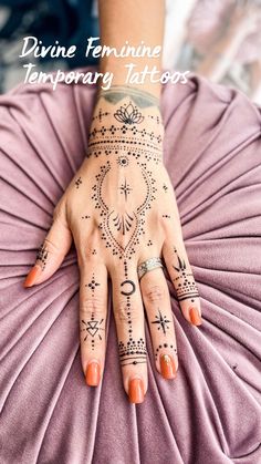 a woman's hand with tattoos on it sitting on top of a purple pillow