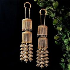 two pairs of gold toned earrings hanging from chains with dangling pearls and beads on them