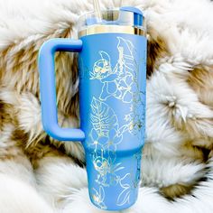 a blue travel mug sitting on top of a furry blanket