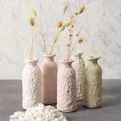 three vases with flowers in them sitting on a table next to a pile of snow