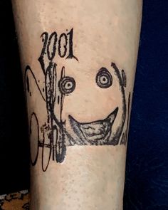 a tattoo on the leg of a person with scissors in his hand and an image of a smiling face