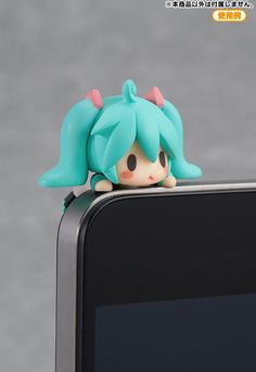 a small doll sitting on top of a cell phone