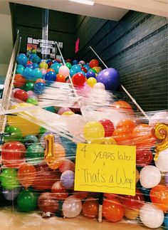 a bunch of balloons that are in some kind of room with a sign on it