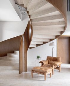 a living room with a couch and chair under a spiral staircase