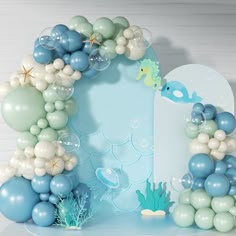 a blue and white balloon arch with fish, seahorses and bubbles on it