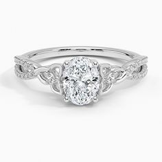 an oval cut engagement ring with twisted shoulders and a center stone surrounded by round diamonds