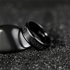 two wedding rings sitting on top of each other in black and silver glittered material