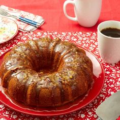 a bundt cake sitting on top of a red plate next to a cup of coffee