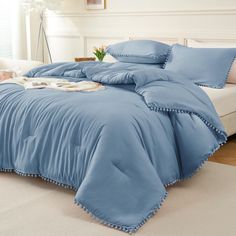 a blue comforter with pom poms on the edges and pillows in a bedroom