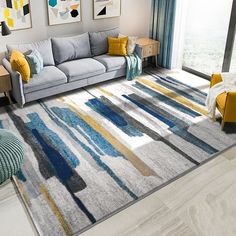 a living room with a gray couch, yellow and blue rugs and pictures on the wall