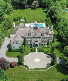 an aerial view of a large mansion with pool and landscaping in the foreground, surrounded by lush green trees