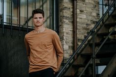 a young man standing in front of a set of stairs next to a brick building