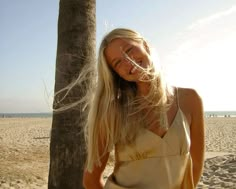 a woman standing next to a palm tree on a beach