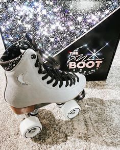 a pair of white roller skates sitting on top of a carpeted floor next to a box