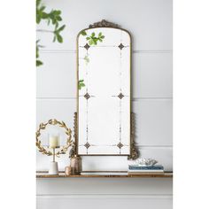 a mirror sitting on top of a wooden shelf next to a vase and candle holder