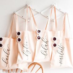 four pink bags with black writing on them hanging from the wall next to a rocking chair