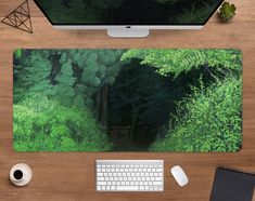 a computer desk with a keyboard, mouse and monitor on it in front of a forest scene