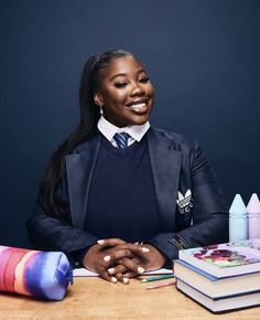 a woman sitting at a table with books and crayons