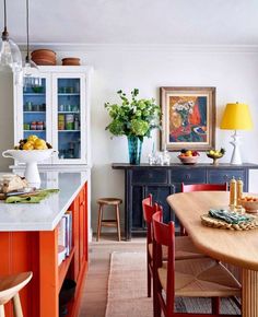 an image of a kitchen setting with orange and red chairs on the countertop, in front of a blue cabinet