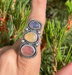 This ring features a unique color combination with a pinky-red Strawberry Quartz, Yellow Aventurine, and Blue Tanzanite set in a handcrafted .925 Sterling Silver design with twist borders and embellishments. The ring has a split shank style and is a Size 7 US.  IG: @wildrose.silver Please messsage me about custom sizing and gemstones! Multicolor Ruby Ring Gift, Adjustable Rainbow Gemstone Ring, Multicolor Oval Ruby Ring Gift, Multicolor Oval Ruby Ring For Gift, Multicolor Natural Stone Rings For Anniversary, Anniversary Rings With Multicolor Natural Stones, Multicolor Sapphire Ring For Gift, Unique Multicolor Birthstone Jewelry, Spiritual Multicolor Multi-stone Rings