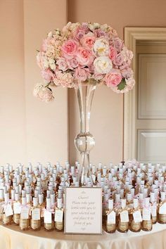 a table topped with lots of bottles filled with pink flowers and baby's breath