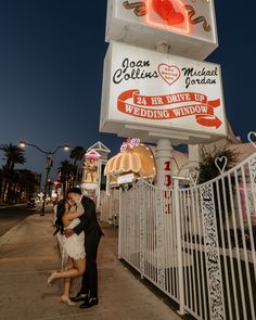 a couple kissing in front of a wedding window sign