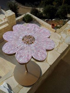 a pink flower shaped table sitting on top of a stone wall