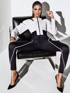 a woman sitting on top of a chair in black and white clothes with her legs crossed