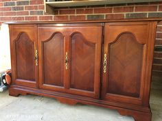 a large wooden cabinet sitting in front of a brick wall