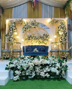 a stage set up for a wedding with blue couches and white flowers on it